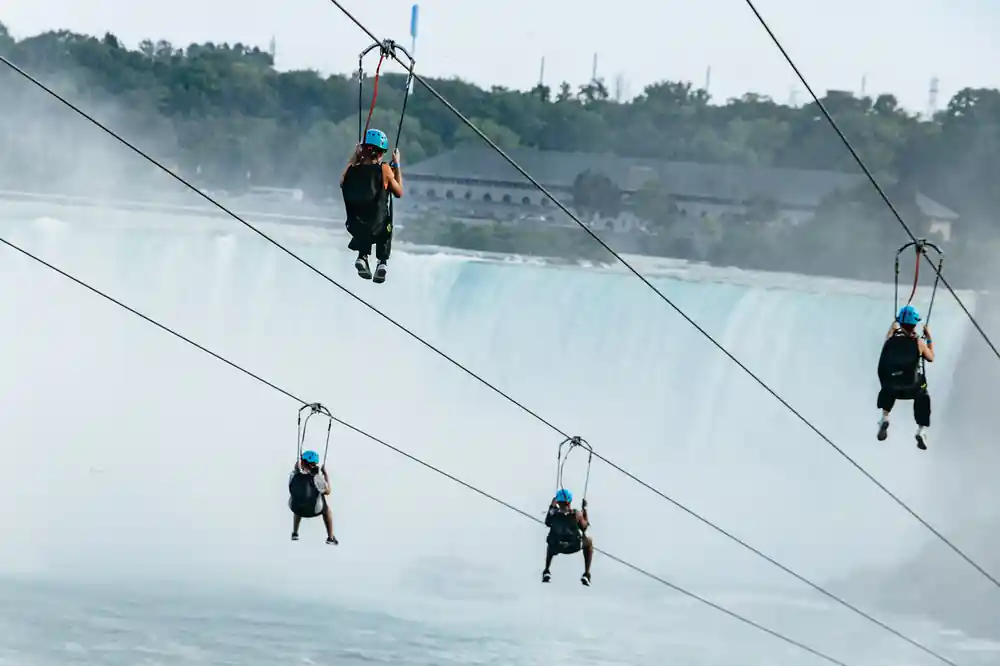 Three riders descending with the falls filling the background