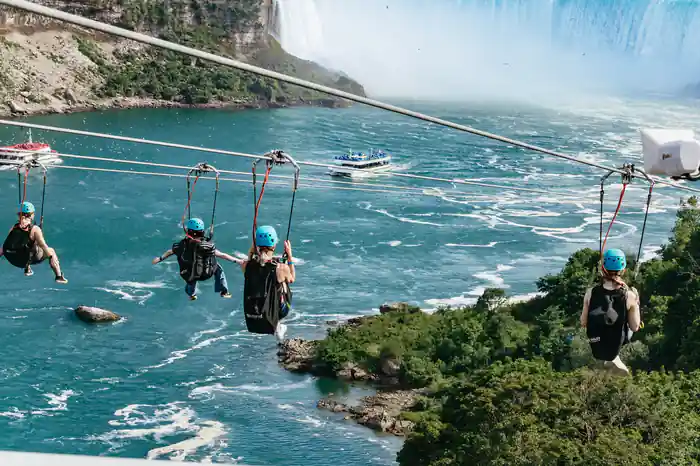 Two riders on parallel lines above the river with the falls behind